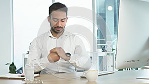 Business man using using sanitizer while working on a computer in an office. Entrepreneur cleaning and disinfecting his