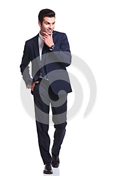 Business man walking while holding one hand to his chin