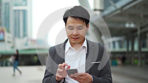 Business man walking and using smartphone in city