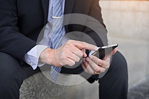 business man wearing black suit and using modern smartphone in o