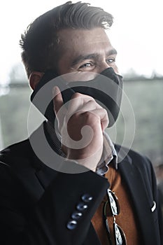 Business man wearing coronavirus medical face mask while using smartphone