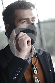 Business man wearing coronavirus medical face mask while using smartphone