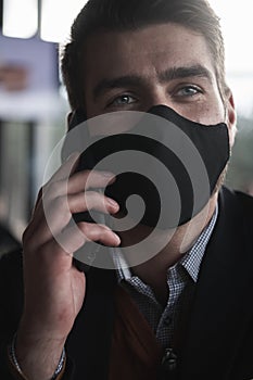 Business man wearing coronavirus medical face mask while using smartphone