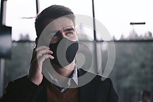 Business man wearing coronavirus medical face mask while using smartphone