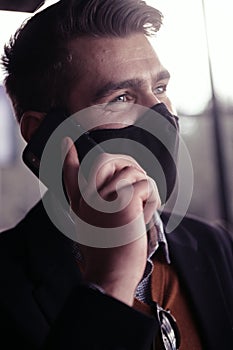 Business man wearing coronavirus medical face mask while using smartphone