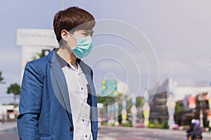 The business man wearing protection face mask against coronavirus, PM 2.5 and cold while standing on escalator. Coronavirus and