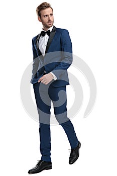 Business man wearing a suit walking with hands in pocket