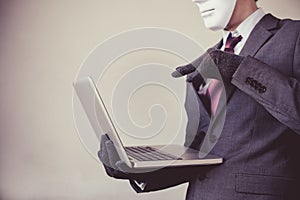 Business man in white mask wearing gloves and using computer - fraud, hacker, theft, cyber crime