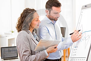 Business man and woman, analysing stats on a paperboard