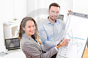 Business man and woman, analysing stats on a paperboard