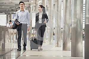 Business man and woman  Dragging suitcase luggage bag,walking to passenger boarding in Airport,travel to work.Asian tourist men