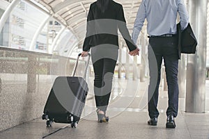 Business man and woman Dragging suitcase luggage bag,walking to passenger boarding in Airport,travel to work.Asian tourist men and