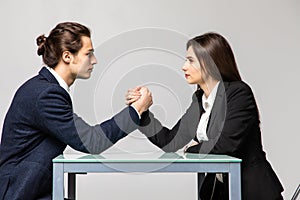 Business man and woman are fighting in their arms, arm wrestling between male and female. Family quarrel, showdown, division of
