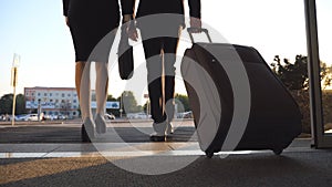 Business man and woman with luggage going from the airport to city street. Follow to young businessman carrying suitcase