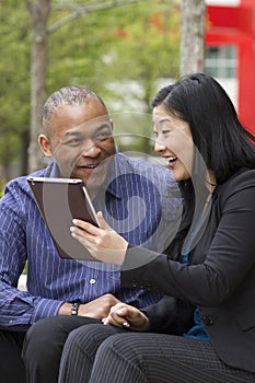 Business man and woman outside on their break with their tablets