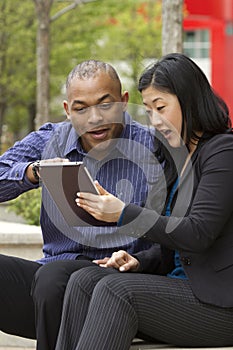 Business man and woman outside on their break with their tablets