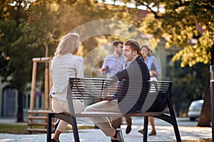 Business man and woman sitting at bench at park and talking