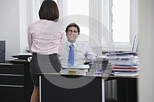 Business man and woman talking in office smiling