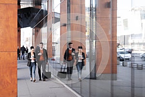 Business man and woman walking and drinking coffee. Businesspeople traveling together with luggage