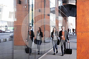 Business man and woman walking and drinking coffee. Businesspeople traveling together with luggage