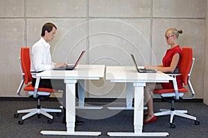 Business man and woman working in correct sitting posture with laptops sitting on chairs