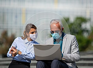 Business man and woman working on laptop on outdoor stairs