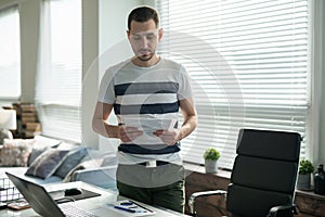 Business man working with laptop at his desk in the office holds documents