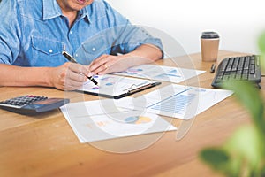 Business man working on a laptop tablet and graph data documents on his desk in home office