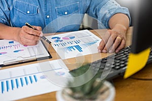 Business man working on a laptop tablet and graph data documents on his desk in home office