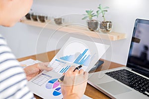 Business man working on a laptop tablet and graph data documents on his desk in home office