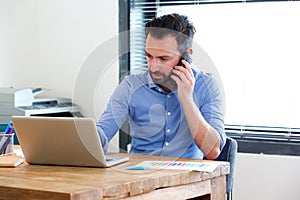 Business man working on laptop and talking on mobile phone