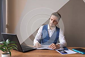 Business man works in an office with laptop and documents on his desk in shirt