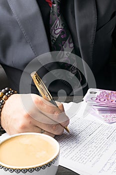 Business man writing a contract at the table and working on documents in the office,business concept. Cofee time