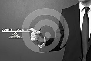 Business man writing Quality and Quantity - Balance Concept