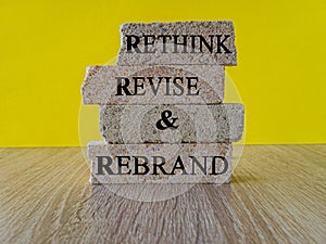 Business management branding concept of rethink revise and rebrand words on brick blocks. Beautiful yellow background. Wooden
