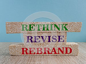 Business management branding concept of rethink revise and rebrand words on brick blocks. Wooden table