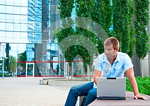 Business manwith laptop in front of modern business building photo