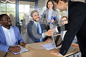 Business meeting associates shaking hands in office.