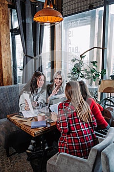 Business meeting in a cafe, four young women sitting at a table and discussing documents