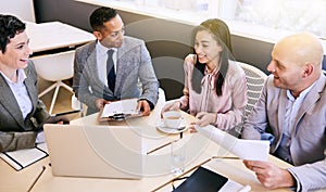 Business meeting between four professional executives in conference room