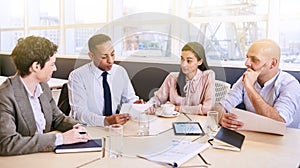 Business meeting between four professional executives in conference room