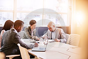 Business meeting between four professional executives in conference room