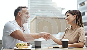Business meetings made better over lunch. Shot of two businesspeople shaking hands while having lunch outside an office.