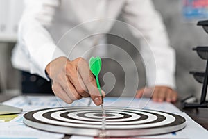 Business men aiming to be successful Business ambitions. Man holds a green darts stabbed to the middle target ,Business target or photo