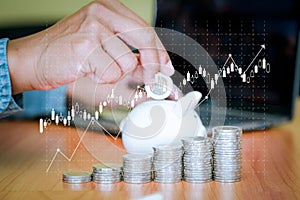 Business men put the coins into the white piggy bank and the coins stacks were lined up in front.