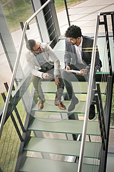 Business men sitting on the stairs. Business people having conve