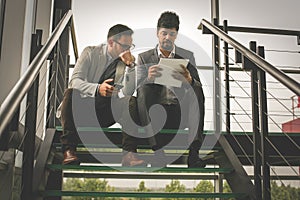 Business men sitting on the stairs. Business people having conve