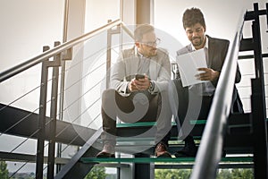 Business men sitting on the stairs. Business people having conve