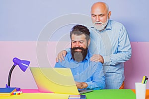 Business men team of two people talk and work together on laptop. Old father and young man looking at laptop screen