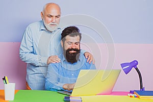 Business men team of two people talk and work together on laptop. Old father and young man looking at laptop screen